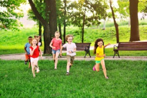 a group of preschoolers running on the grass against the background of the park and greenery. Children Protection Day.