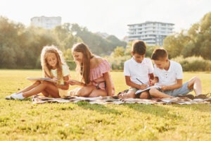 Conception of hobbies. Group of happy kids is outdoors on the sportive field at daytime.