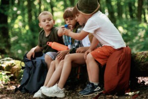 Kids in forest at summer daytime together.