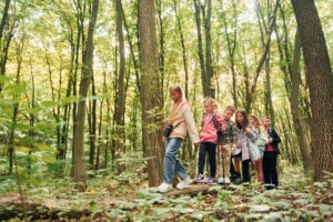 Walking together. Kids in green forest at summer daytime together.